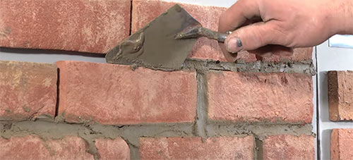 Pointing mortar joint in brick wall using a pointing trowel