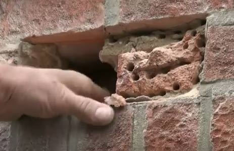 Brick in wall broken up with hammer and bolster