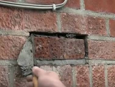 Forcing mortar into gaps around edge to fill holes