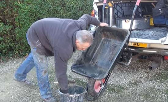 Debris being cleaned off of wheelbarrow using masonry brush