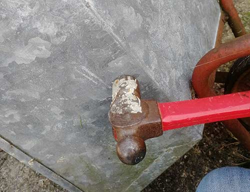 Tapping wheelbarrow tray with hammer
