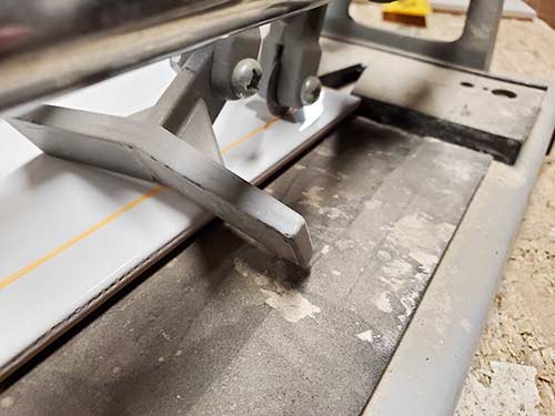 Position tile in cutter so cutting wheel lines up with line