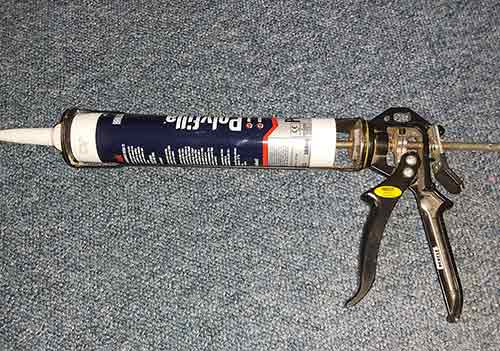 Caulk sealant tube inserted into sealant gun