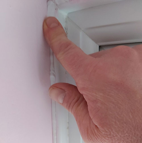 Using a wetted finger to smooth out caulk