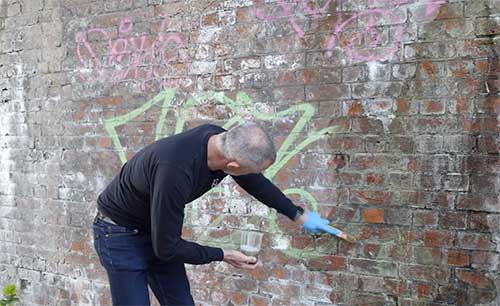Scrubbing graffiti off of a wall