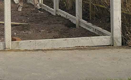 Gravel board slotted down between concrete posts