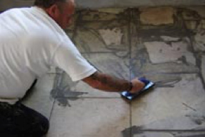 Using a grout float to spread tile grout into joints