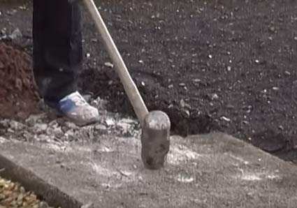 Breaking up a concrete path with a sledge hammer