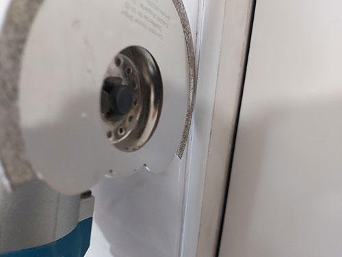 Position edge of grout removing blade on grout