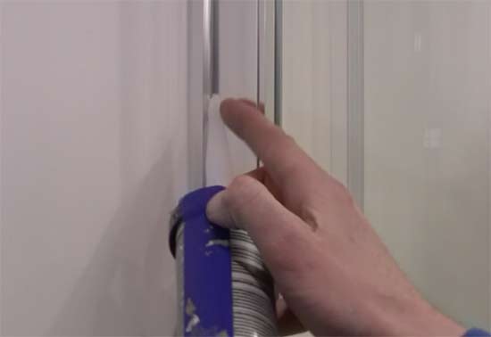 Applying silicone sealant to shower enclosure