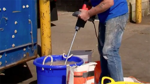 Washing off mixing paddle in bucket of water