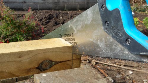 Sawing the top of a fence post at an angle