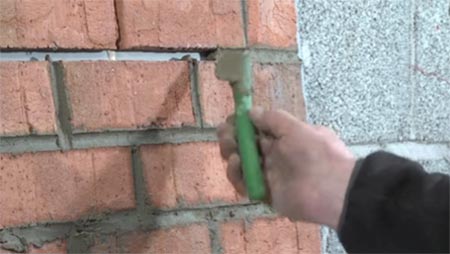 Using a piece of hosepipe to repoint brickwork