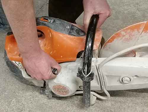 Hold the top handle of the saw and pull start cord