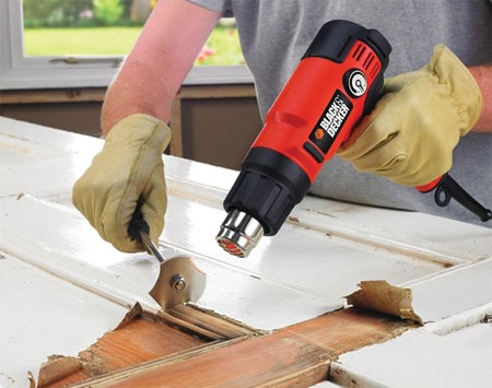 Using a heat gun to strip paint from a door