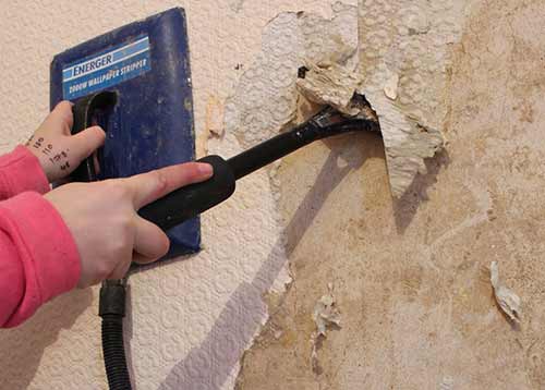 Stripping off wallpaper with stripping knife