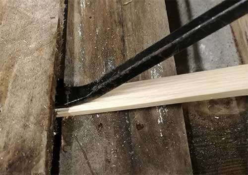 Prying up first floorboard using a pry bar