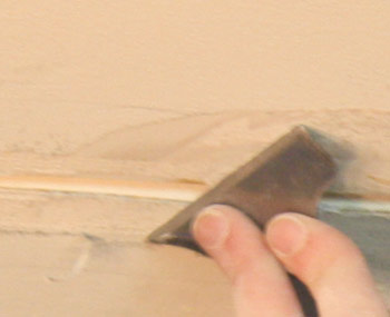 Scraping loose material form ceiling